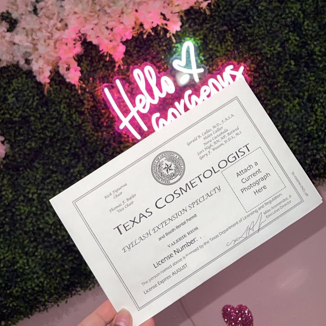 Vee’s Texas Cosmetologist license, Eyelash Extension Specialty, held under her Hello Gorgeous neon sign